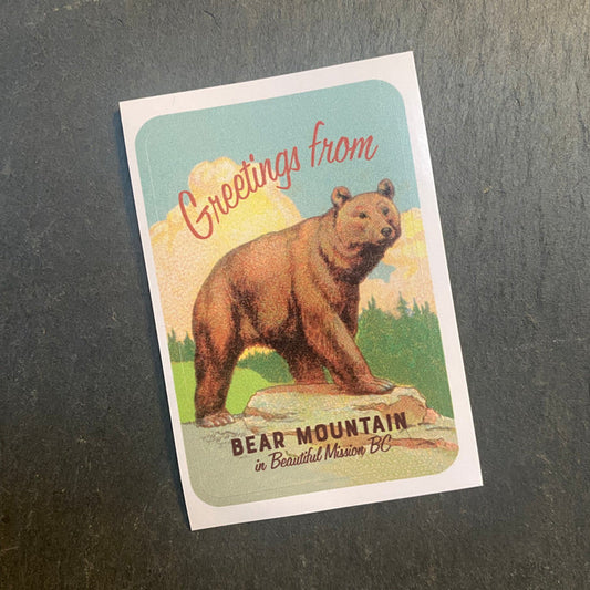 Vintage-style postcard with a bear illustration and text on a dark surface